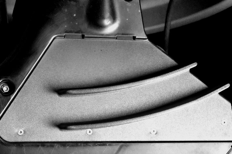 Additively manufactured vehicle panel with two curved stiffening ribs, installed in the car.